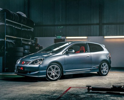 A front left shot of a dark grey 2005 Honda Civic Type R with red interior inside a garage