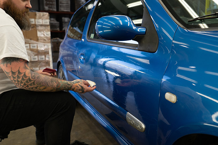 Cleaning the side panel of Clio with clay bar