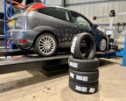 stack of tyres placed in front of grey Ford Focus ST170