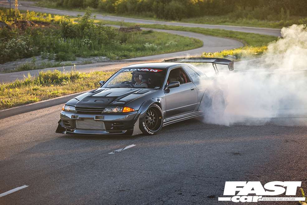 The front left side of a grey modified Nissan Skyline R32 GT R with a smoking back left wheel
