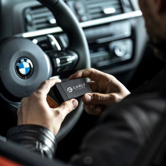 man holding Carly device in car